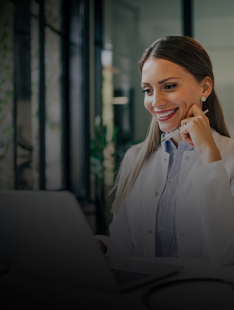 Doctor smiling while looking at laptop